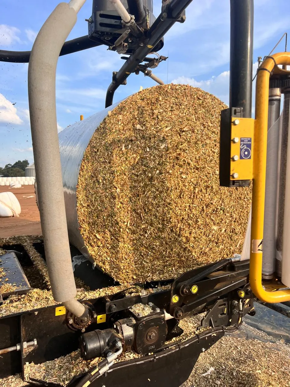 A freshly wrapped round silage bale of chopped feed coming off a baler-wrapper in the field